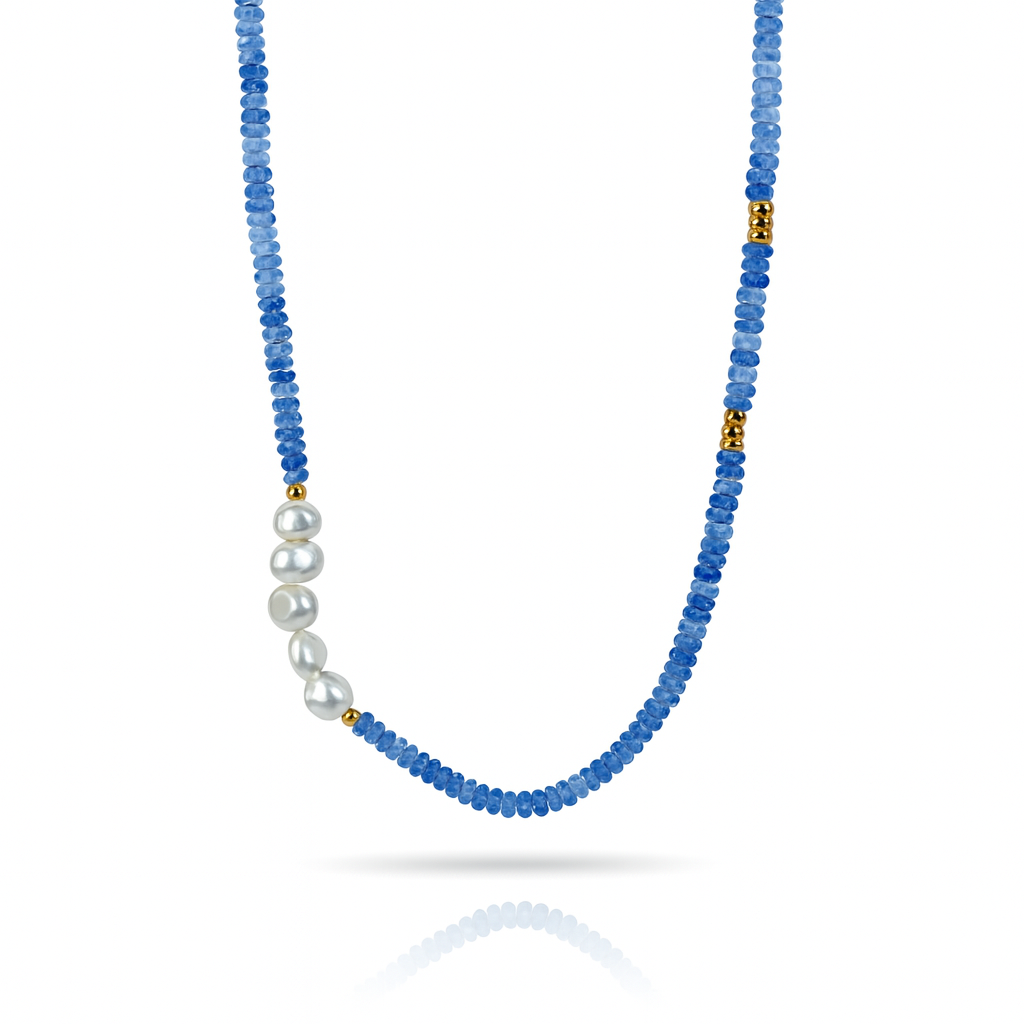 Blue beaded necklace with baroque synthetic pearl center and gold plated stainless steel clasp worn on a woman’s neck
